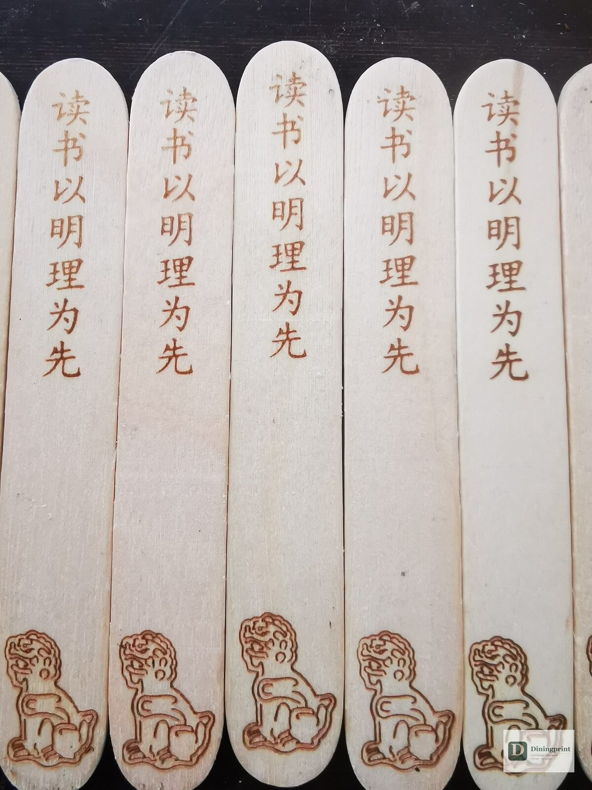 Custom popsicle sticks with laser engraved Chinese calligraphy and a guardian lion logo on birchwood