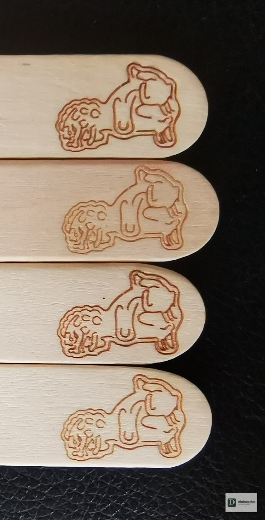 Close-up of a laser engraved guardian lion logo repeated on custom wooden sticks